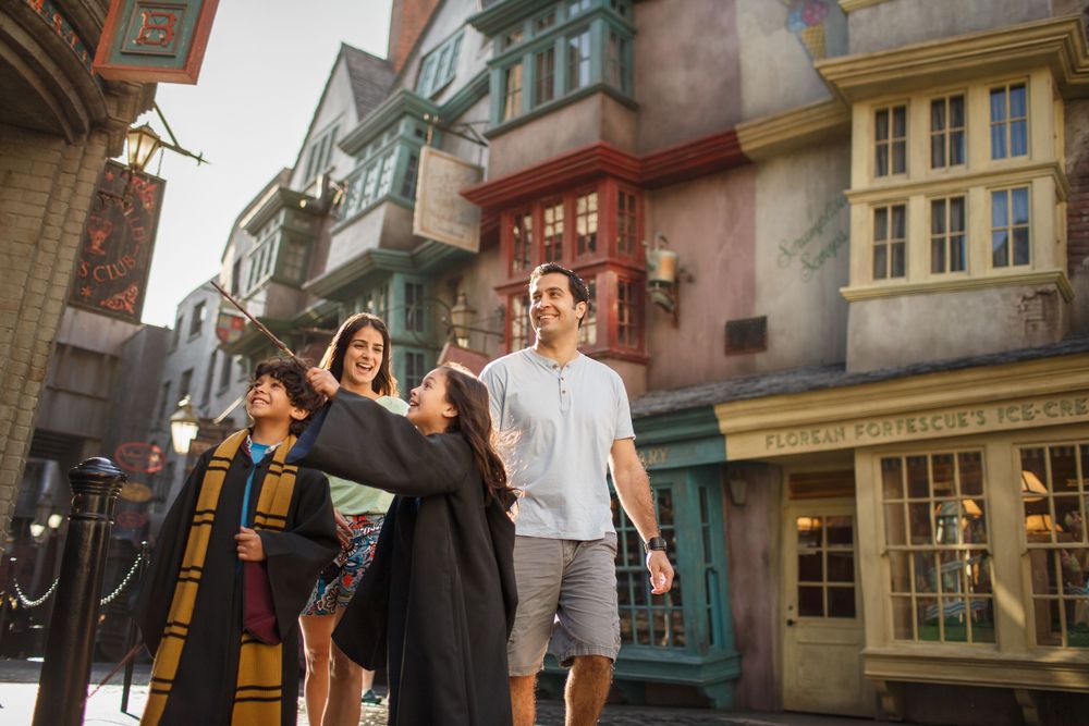 People dressed as characters pose and take pictures in front of themed buildings at the Wizarding World of Harry Potter.
