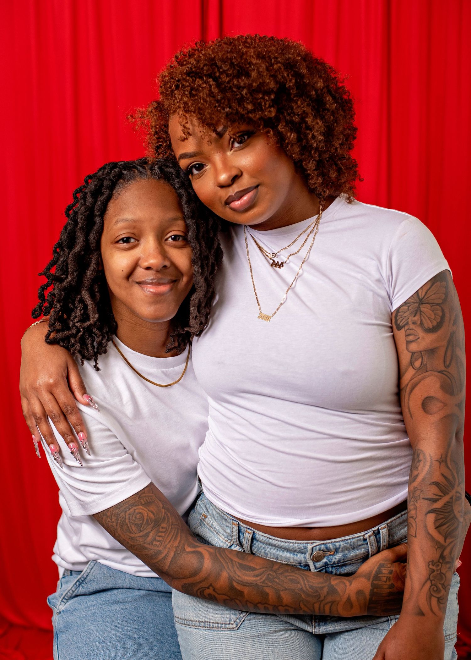 Portrait against red backdrop showing casual style and natural curly hair.