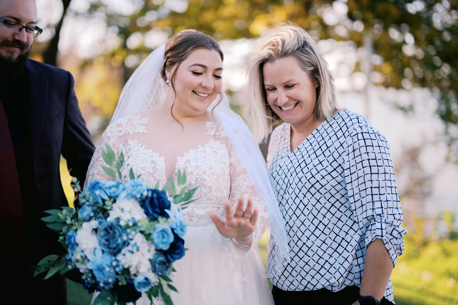 A wedding moment captured outdoors with a stunning blue and white floral bouquet against a fall backdrop.