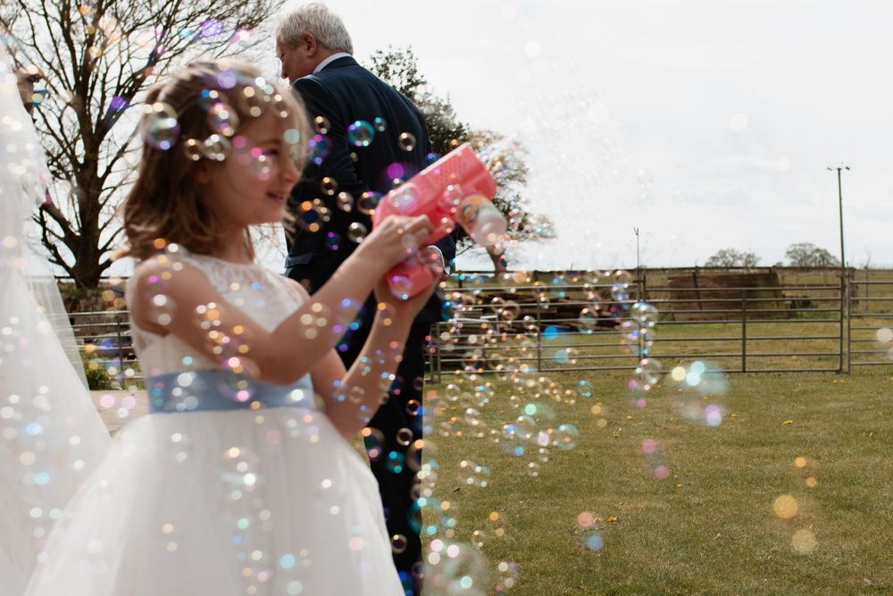 Soap bubbles float through the air at an outdoor celebration against a cloudy sky.