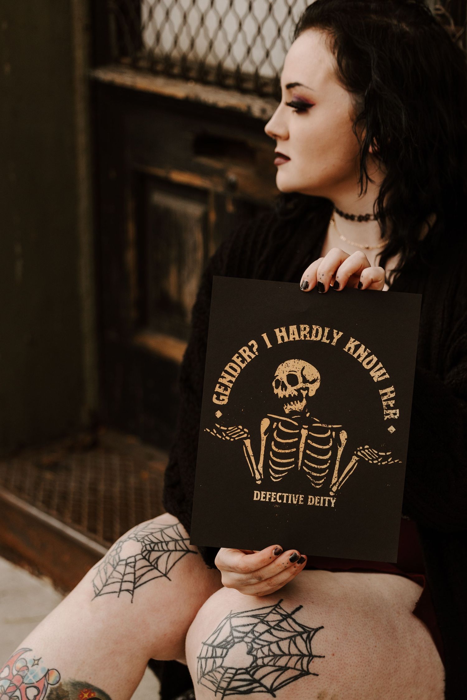 Dark artistic photo showing gothic-styled decor with spiderweb tattoos and skeleton artwork.
