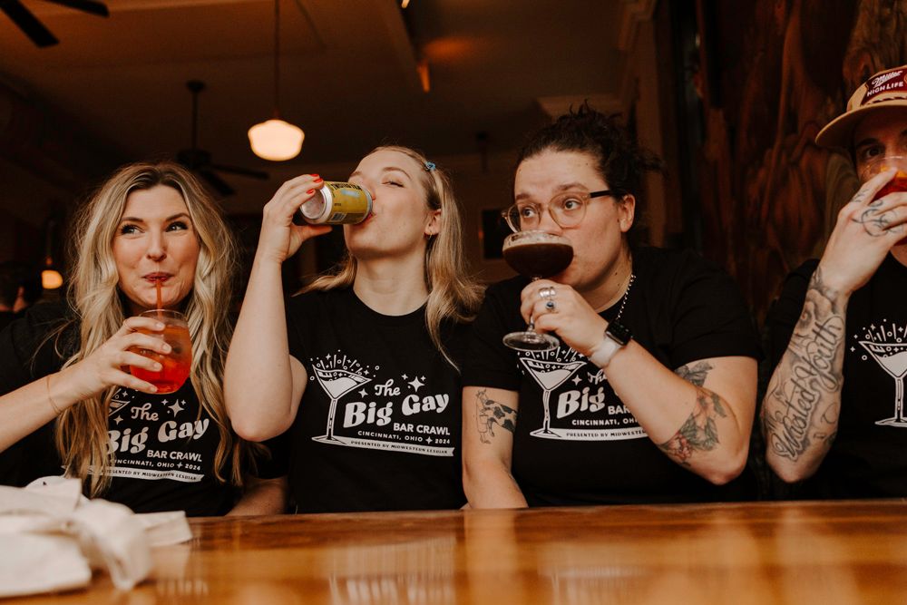 Group taking shots at a bar counter while wearing matching black t-shirts.