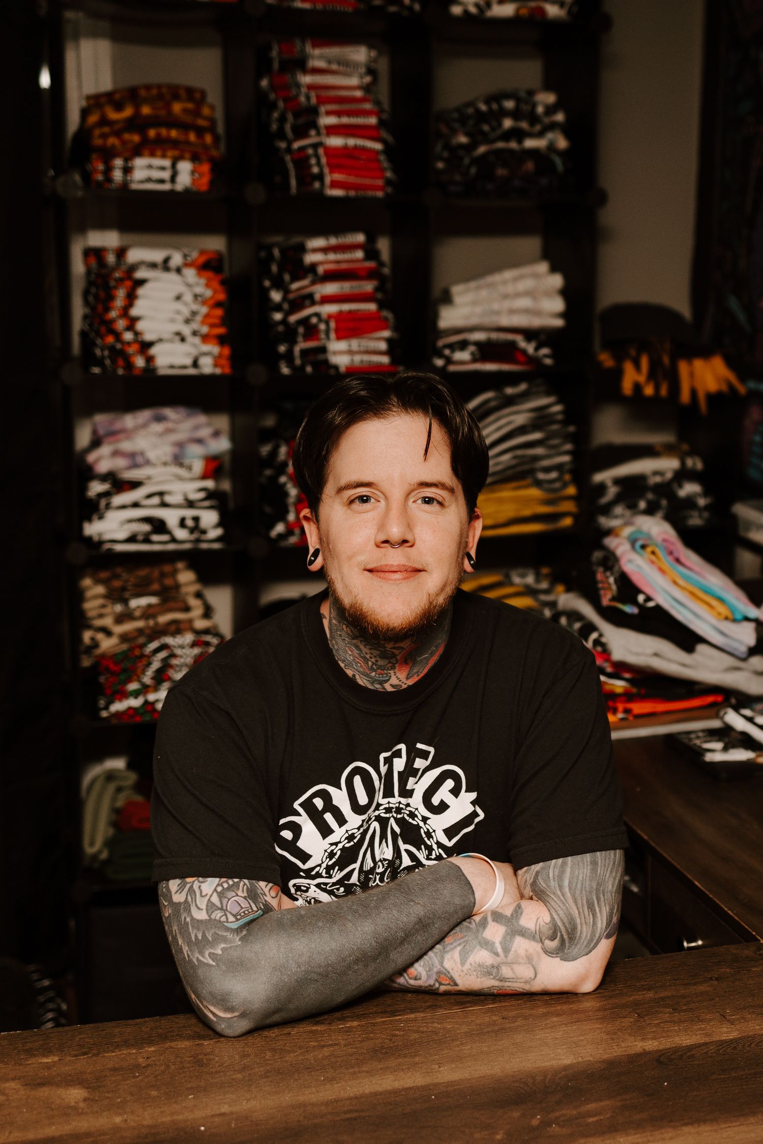 A retail display showing stacks of folded clothing and merchandise on dark shelves.