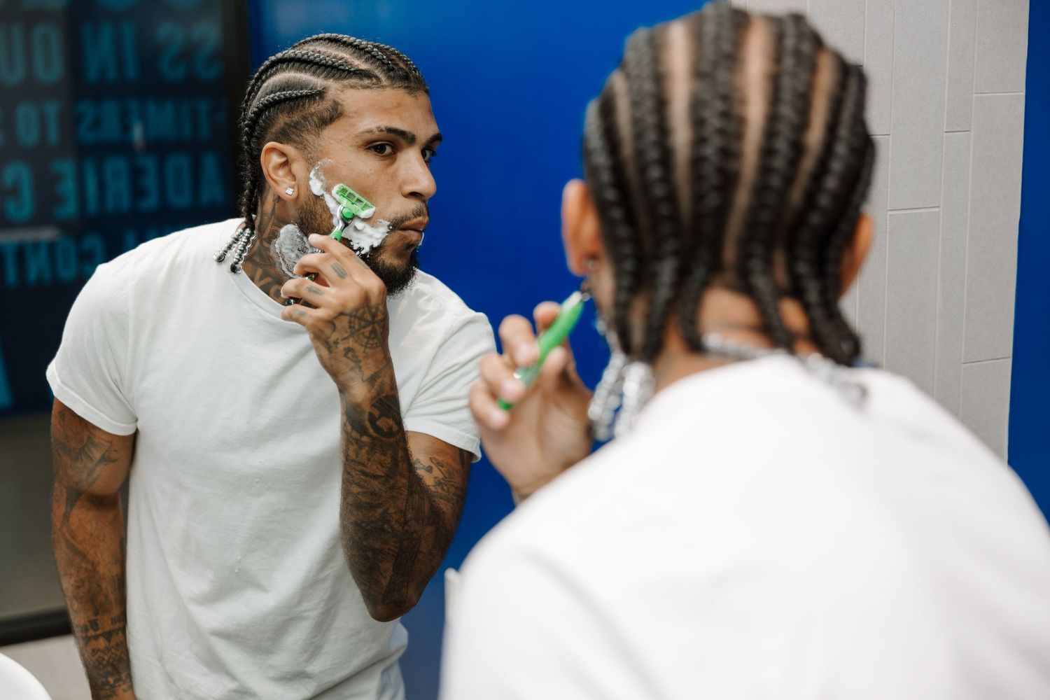 Two people applying shaving cream before grooming in a barbershop setting.
