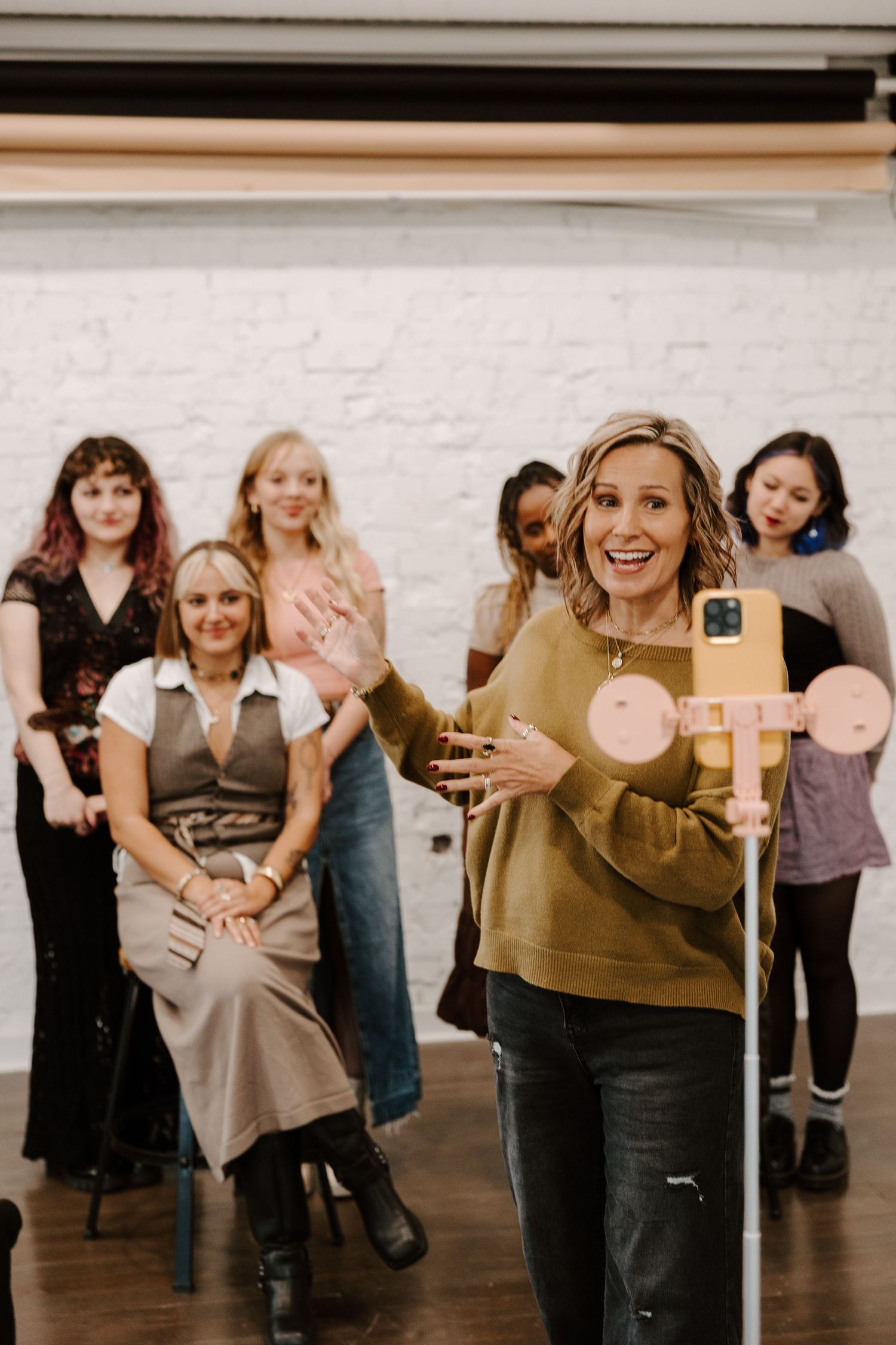 Group gathering in studio space with white brick wall background.