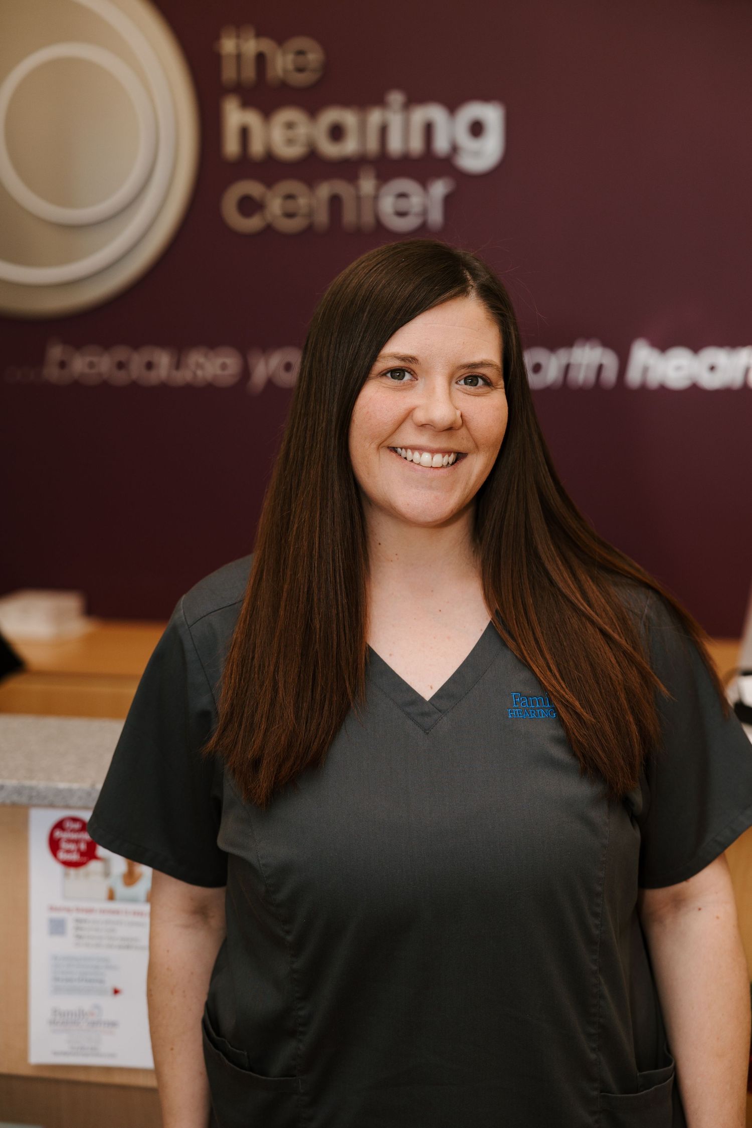 A professional healthcare setting with burgundy wall featuring 'the hearing center' logo.