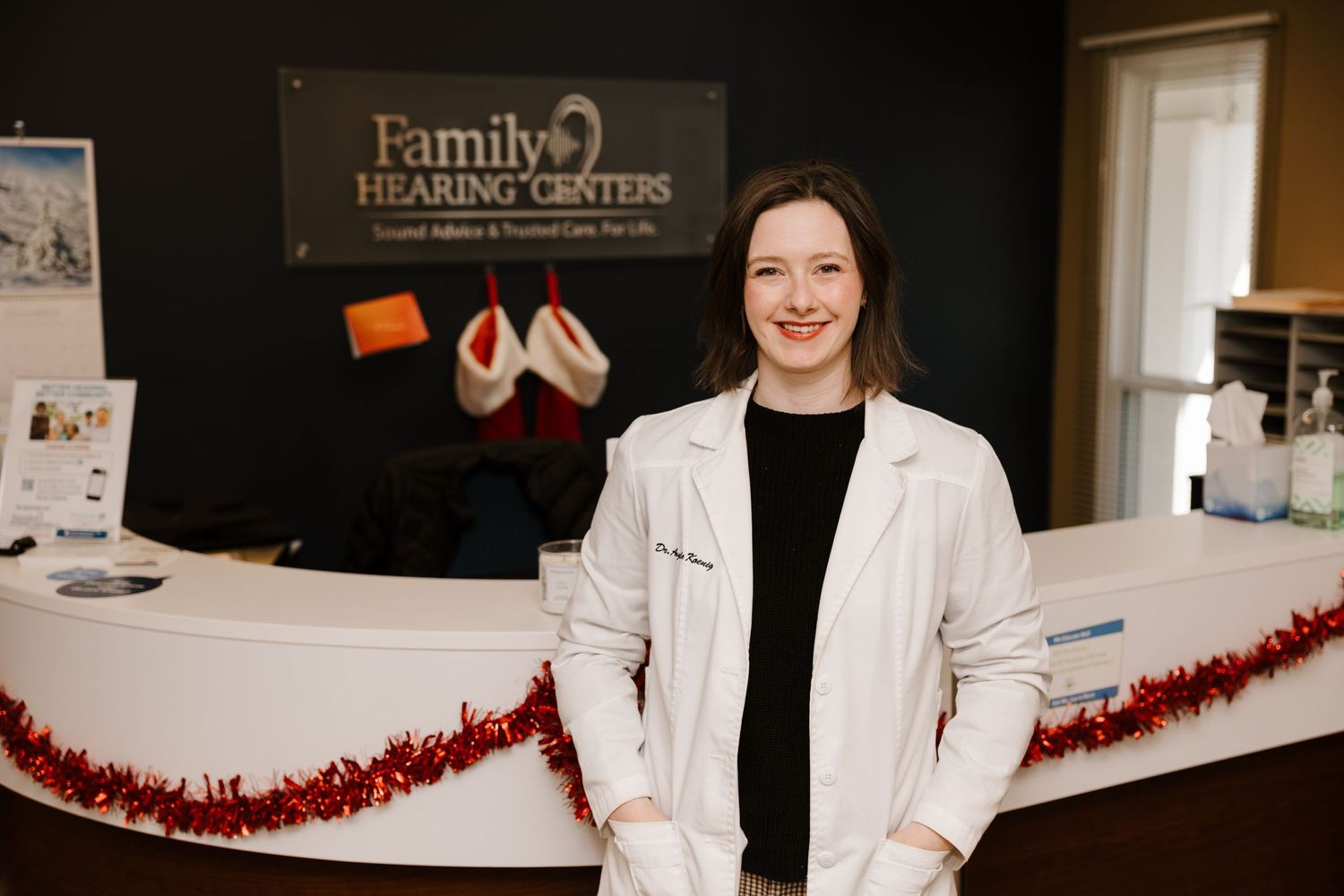 A decorated medical office reception area with red tinsel garland and signage.