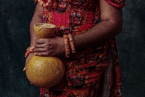Photography Oil painting Close-up of an Igbo brides red traditional dress with beaded necklaces and bracelets holding a golden calabash.