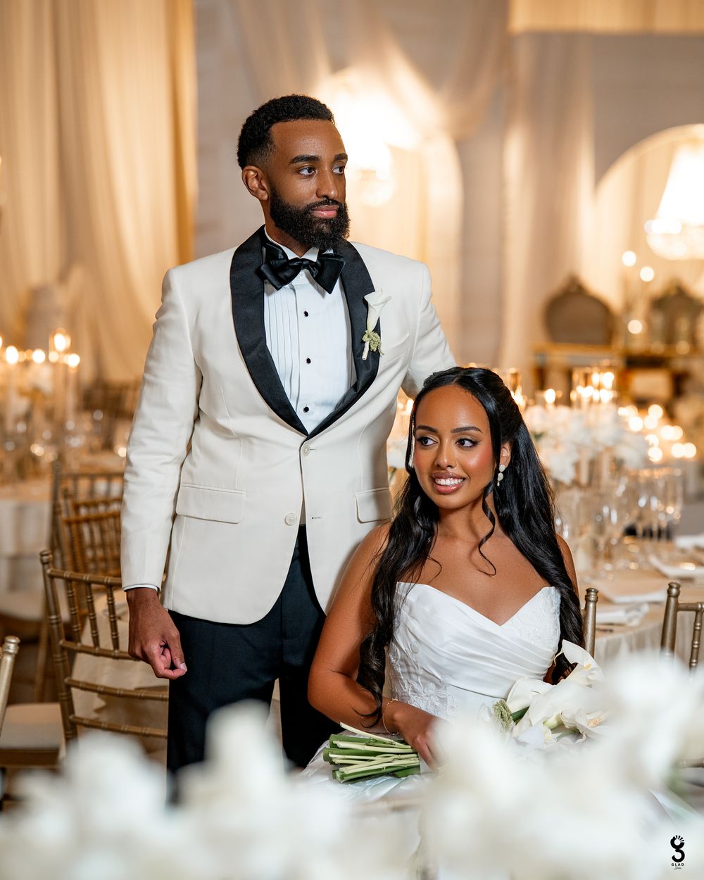 Elegant wedding reception setup with candlelit tables and white decor in a luxurious ballroom setting.