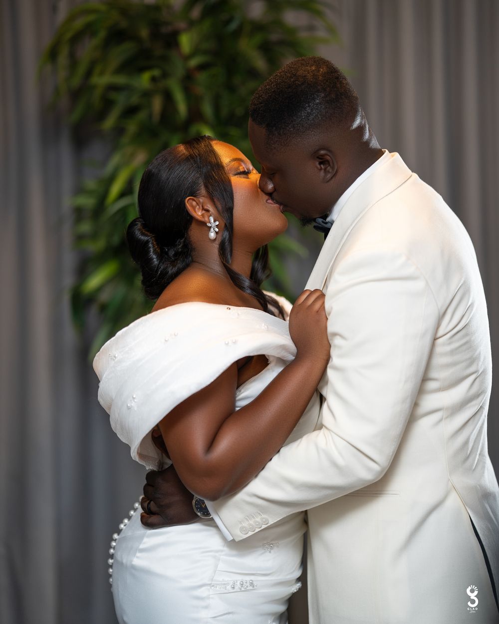 A romantic wedding couple shares an intimate kiss sequence in four progressive photos against a gray wall.