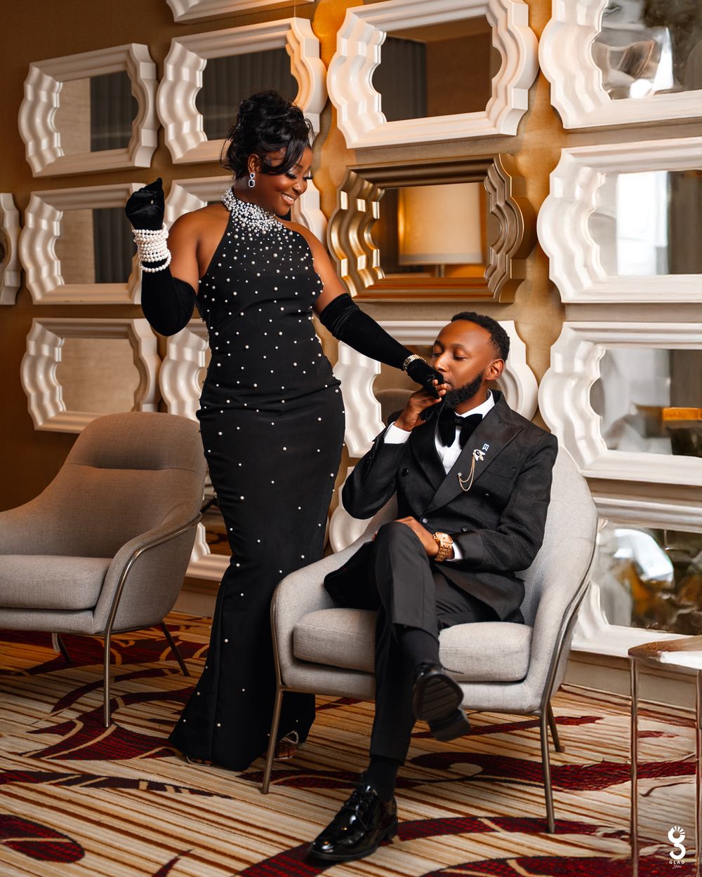 A romantic proposal moment unfolds in an elegantly decorated hotel lobby with white architectural details and warm lighting.