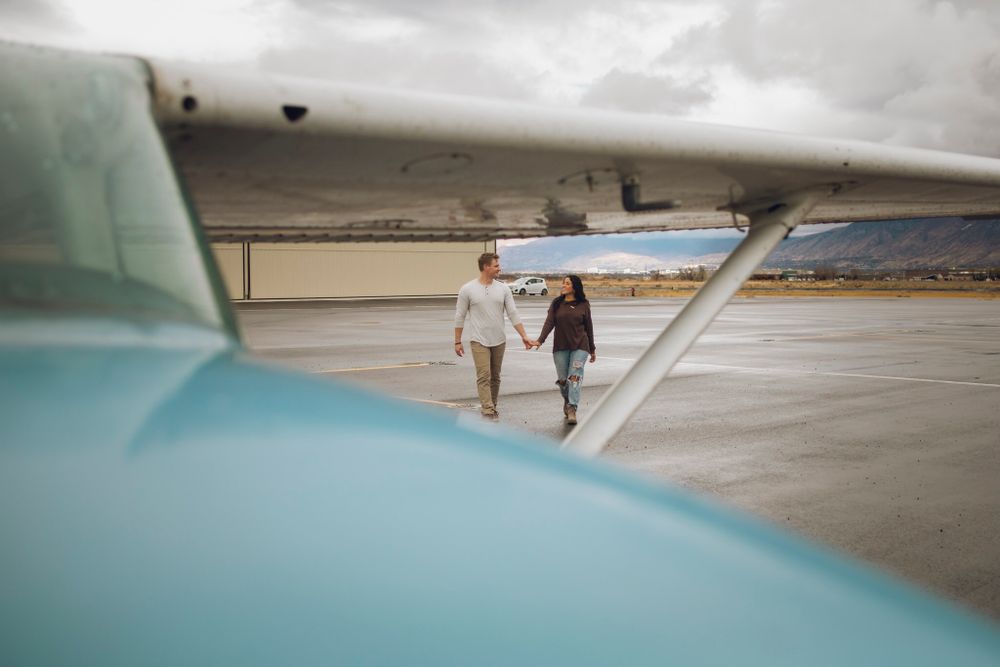 Couple walking toward plane holding hands.