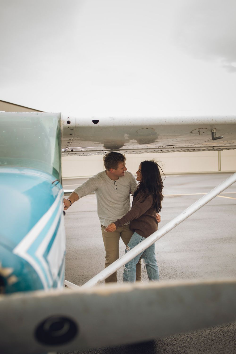 Couple looks at one another as one reaches for the door of the airplane.