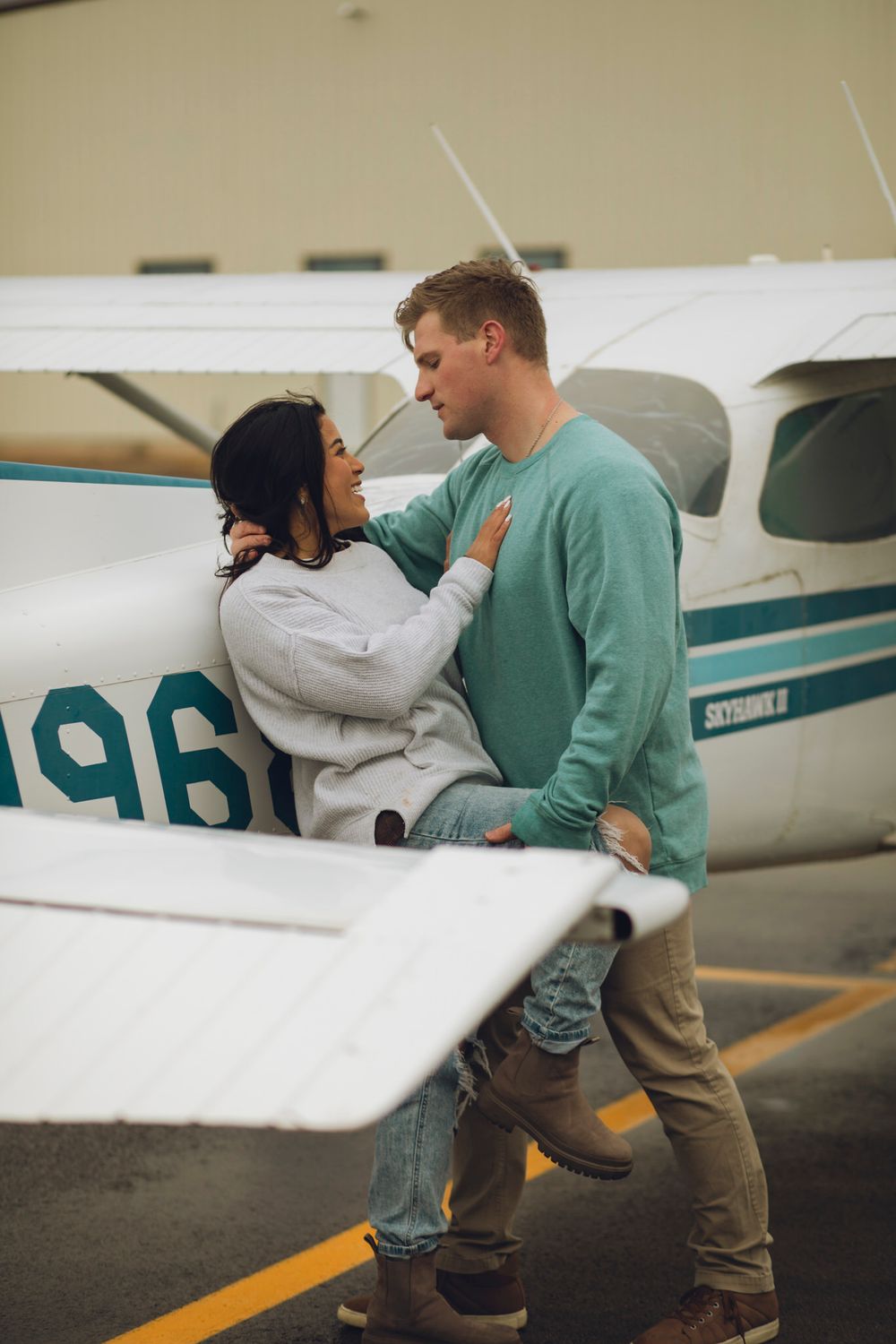 Couple leaning against plane, looking at each other.