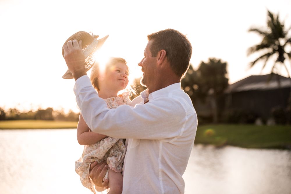 Joyful sunset moment captured between two people in white clothing by the water.