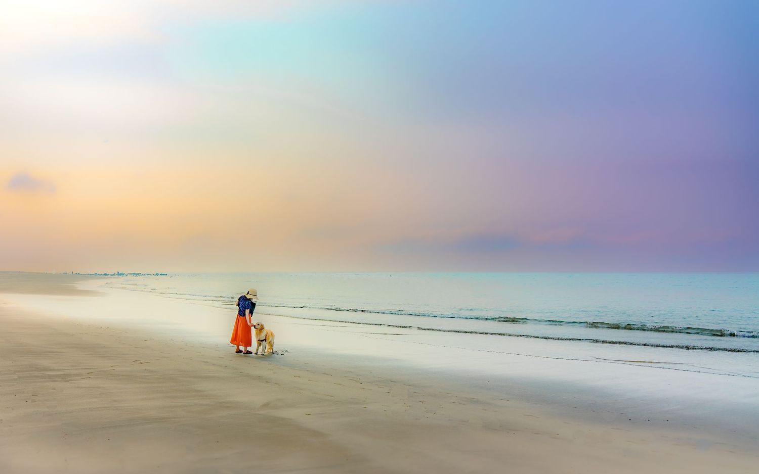 Silhouette of parent and child walking on beach during colorful sunset.