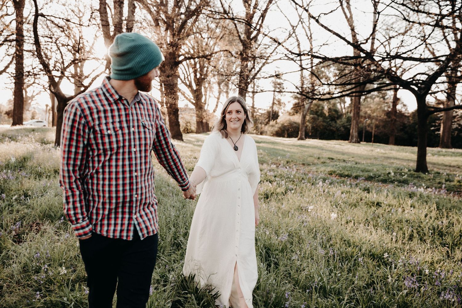 Couple having a playful moment in a sun-drenched meadow setting.