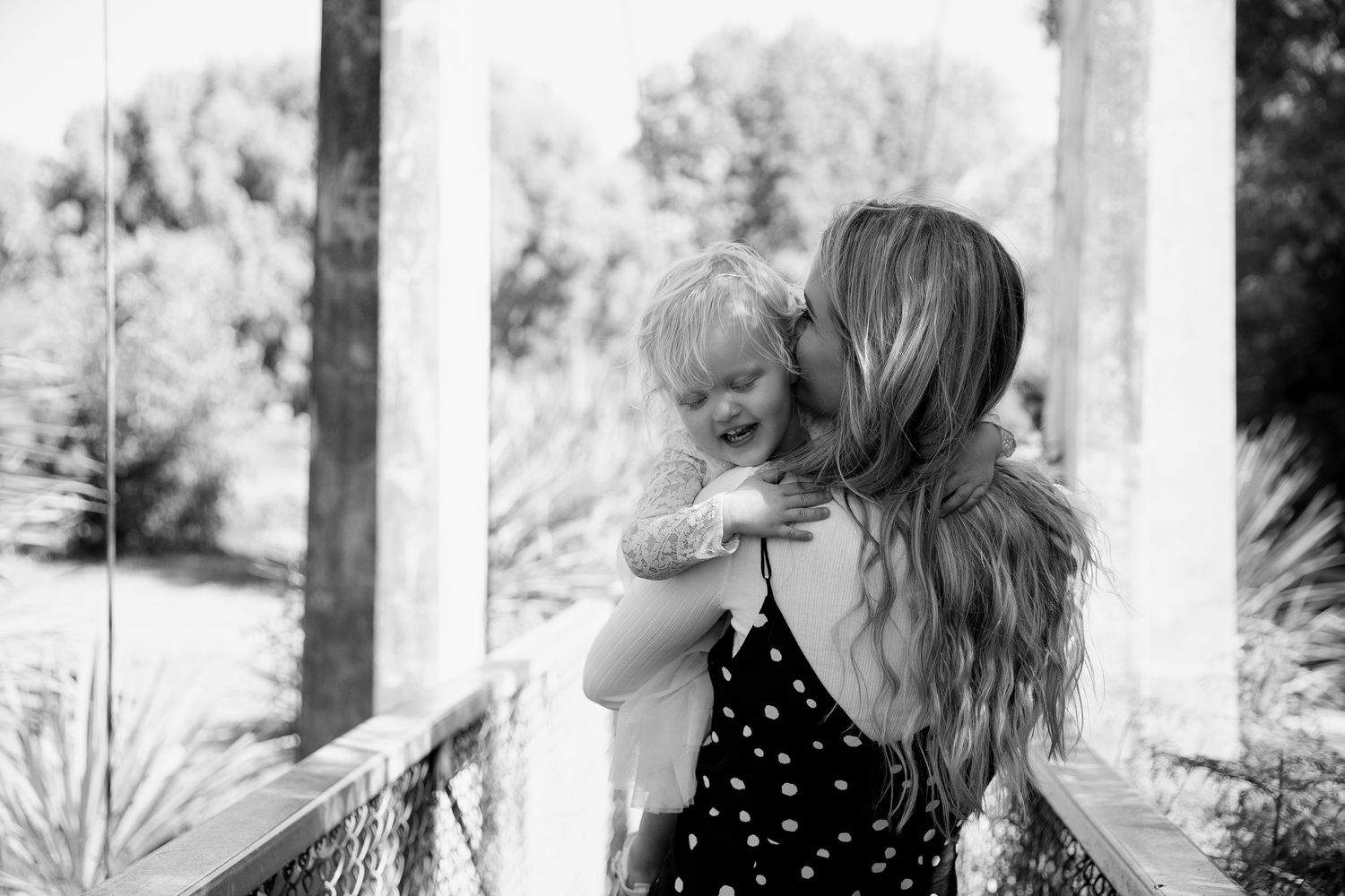 Black and white portrait of mother and child sharing a tender moment on a porch.