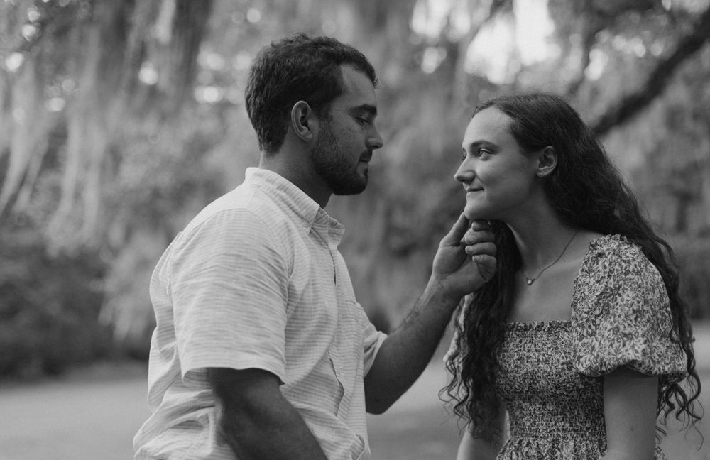 An intimate black and white portrait captured under Spanish moss-covered trees.