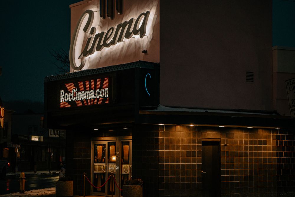 Vintage cinema building exterior with glowing neon sign at dusk.