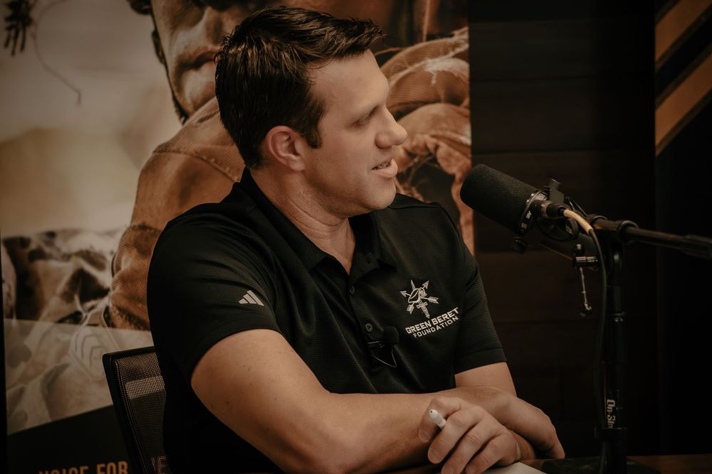 A person wearing a black polo shirt sits at a bar counter with a darker, moody ambiance in the background.