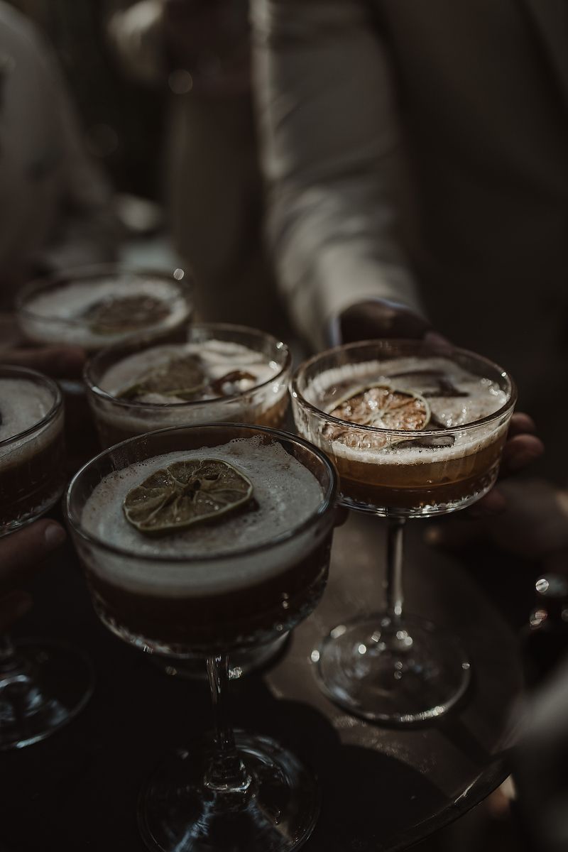 Elegant espresso martini cocktails garnished with dried lime slices served on a dark tray at an upscale bar.