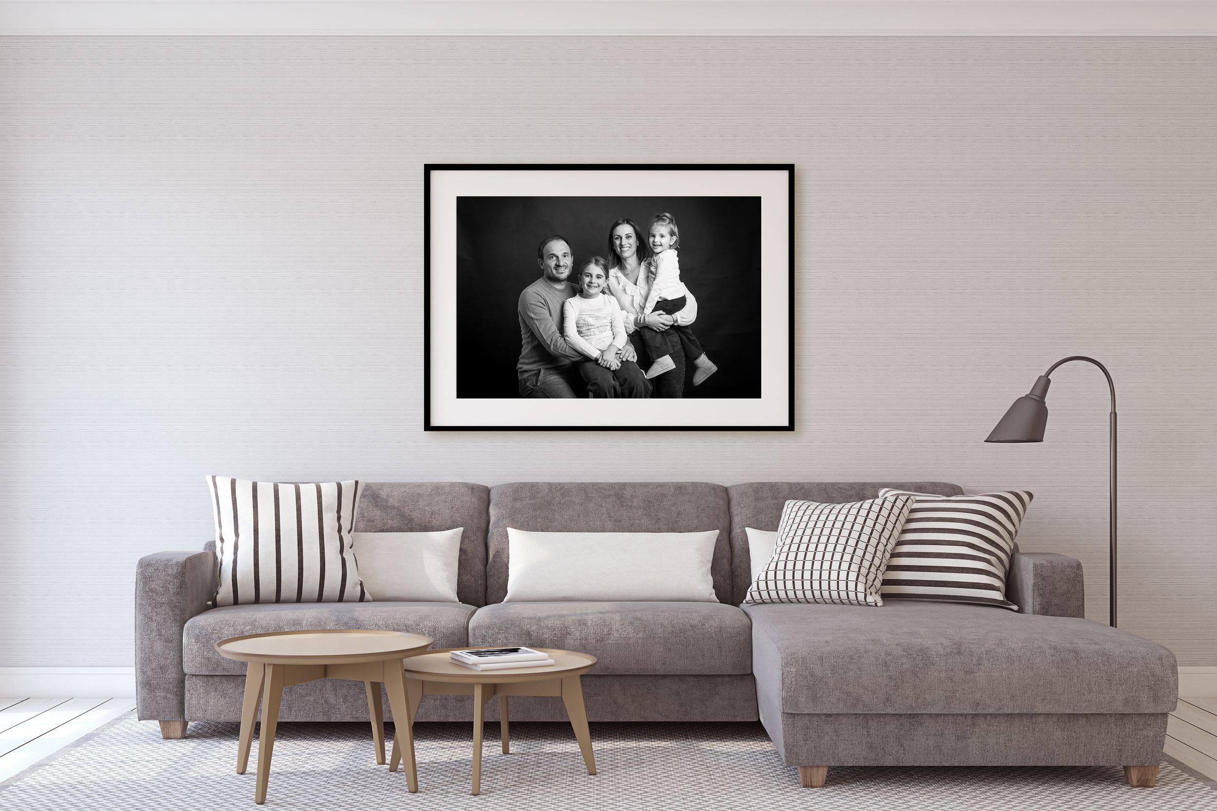 Modern living room with gray sectional sofa, striped pillows, wooden stools, and black and white framed photograph on wall.