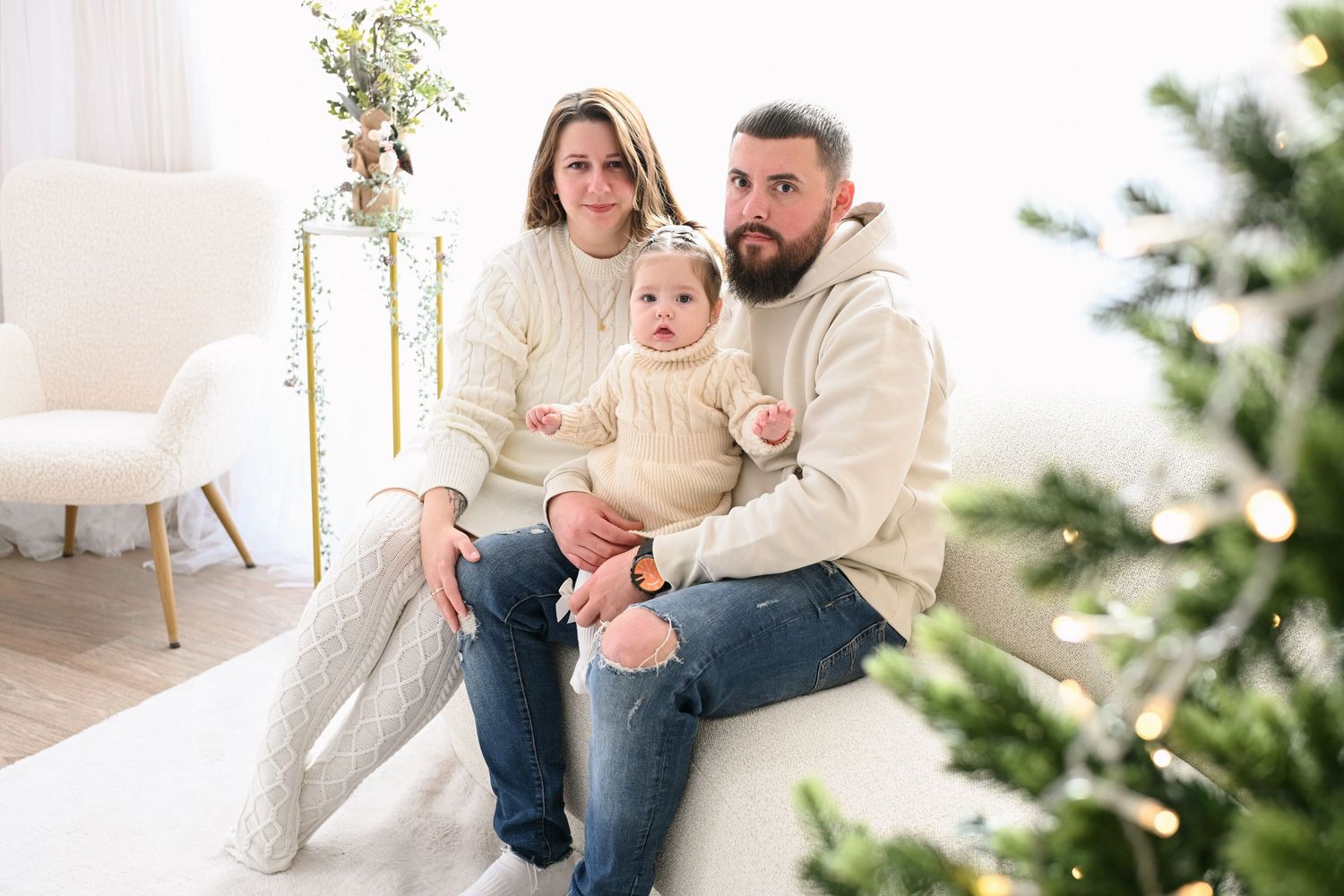 Family portrait session with cream sweaters and jeans in a bright minimalist holiday setting.