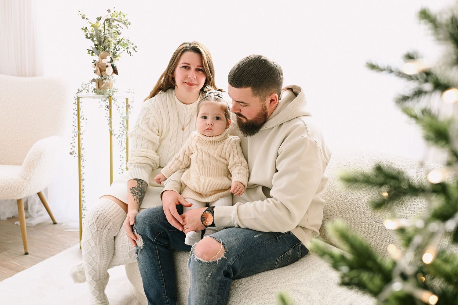 Candid family moments photographed on a white couch with Christmas decor in the background.