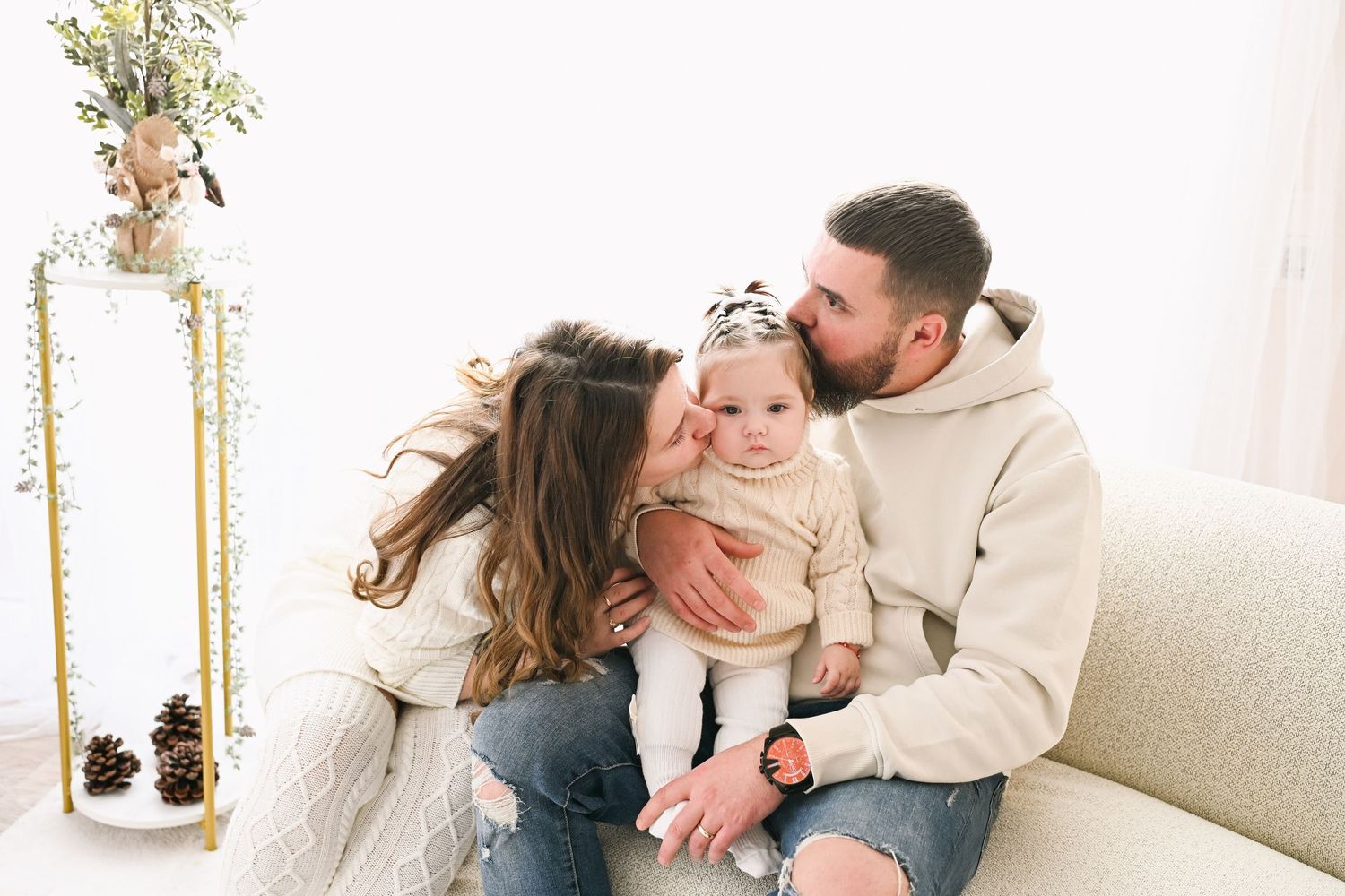 Natural family interactions captured against white walls with holiday greenery and gold accents.
