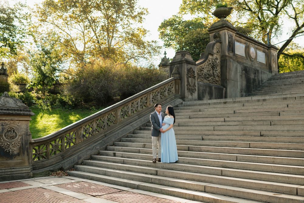 Historic stone staircase with ornate balustrades leads up through a sunlit garden setting on a bright autumn day.