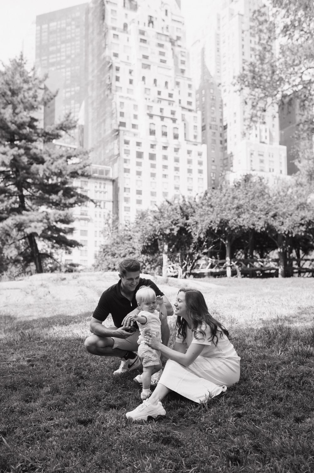 Three black and white photos show people relaxing on a grassy hill with apartment buildings in the background.