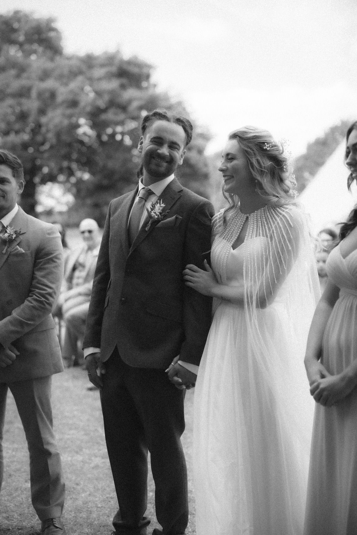 A joyful wedding couple shares a candid moment of laughter together during their outdoor celebration.
