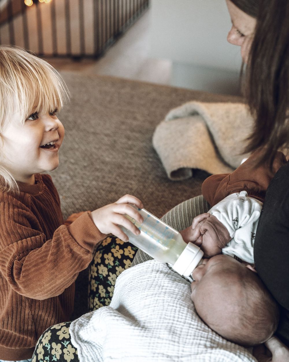 Three candid photos showing tender moments between parent and baby playing on a carpeted floor.
