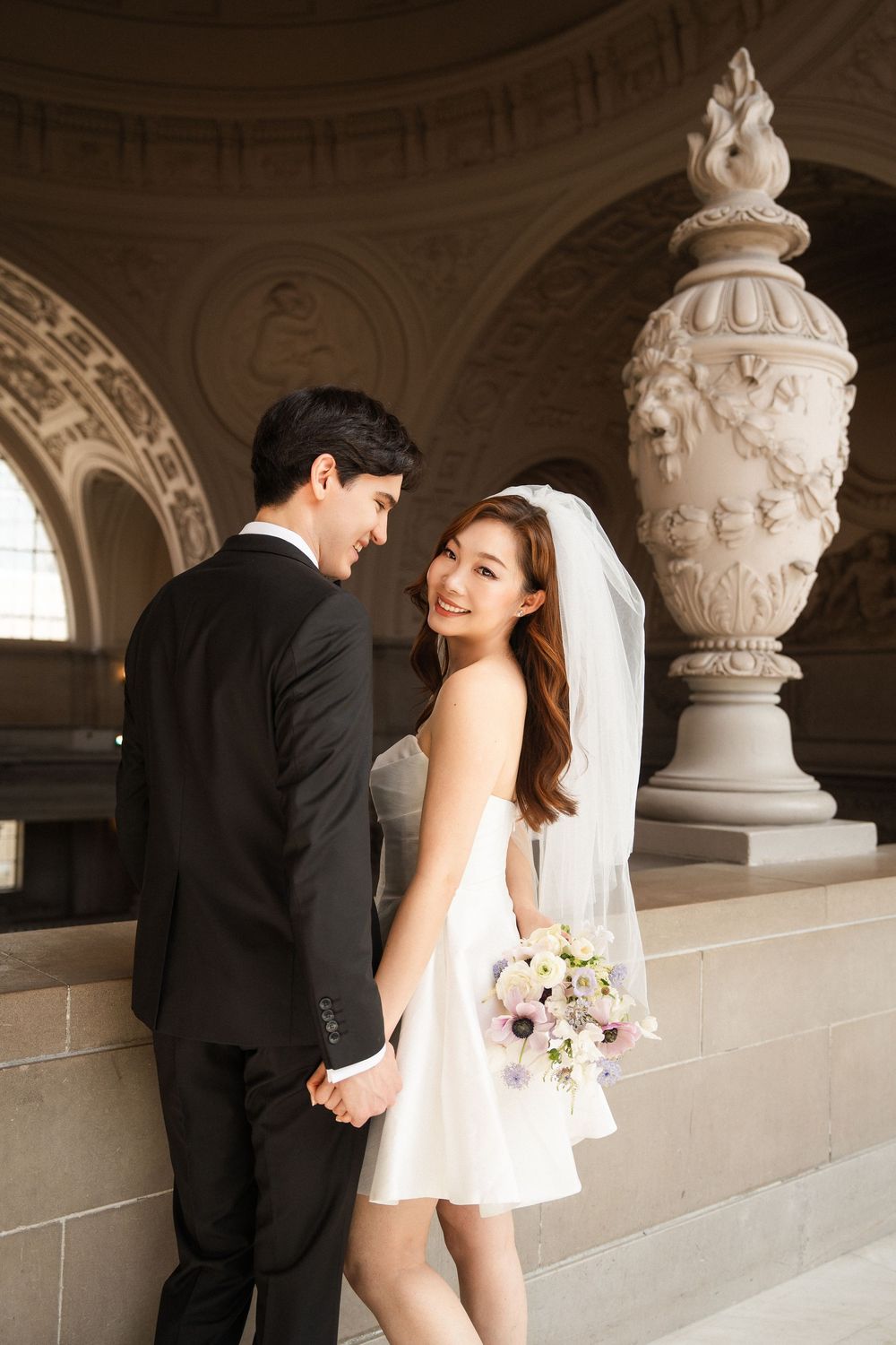 A romantic wedding photo series showing a couple in formal attire posing together in an elegant architectural setting.