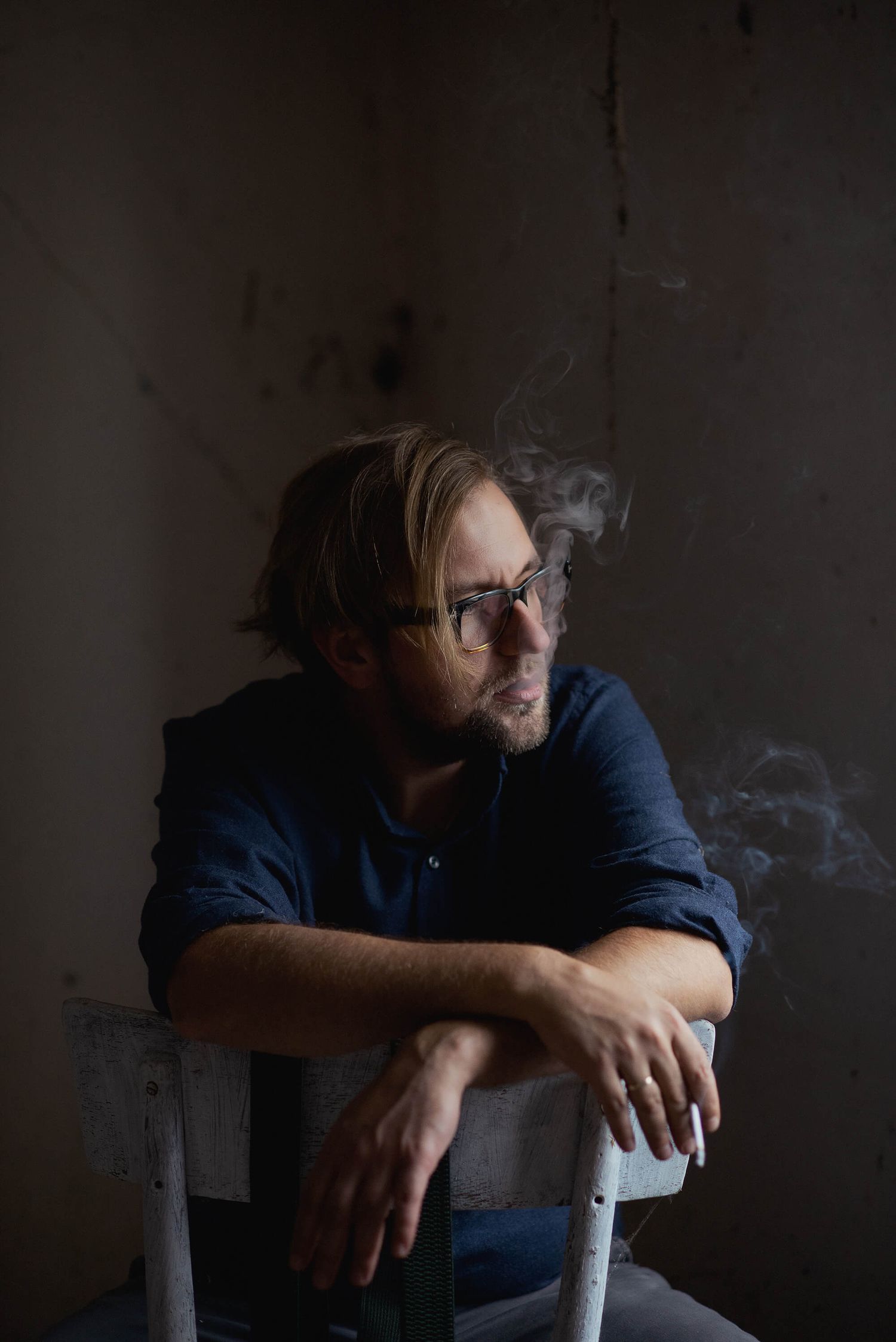 Artystyczny portret mężczyzny w półmroku, wykonany w minimalistycznej przestrzeni – fotografia autorstwa Anety Ludwig.