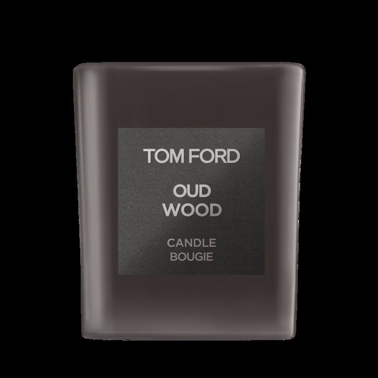 A sleek black Tom Ford Oud Wood candle in a frosted glass vessel with minimalist branding against dark background.