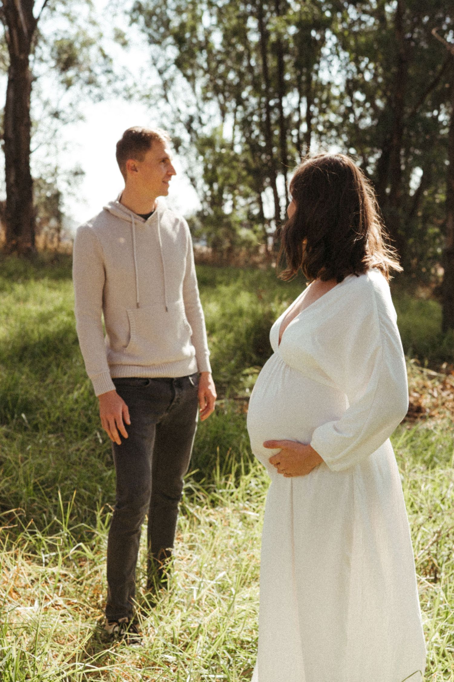 Sun-drenched portraits of couple walking and embracing in natural outdoor setting.