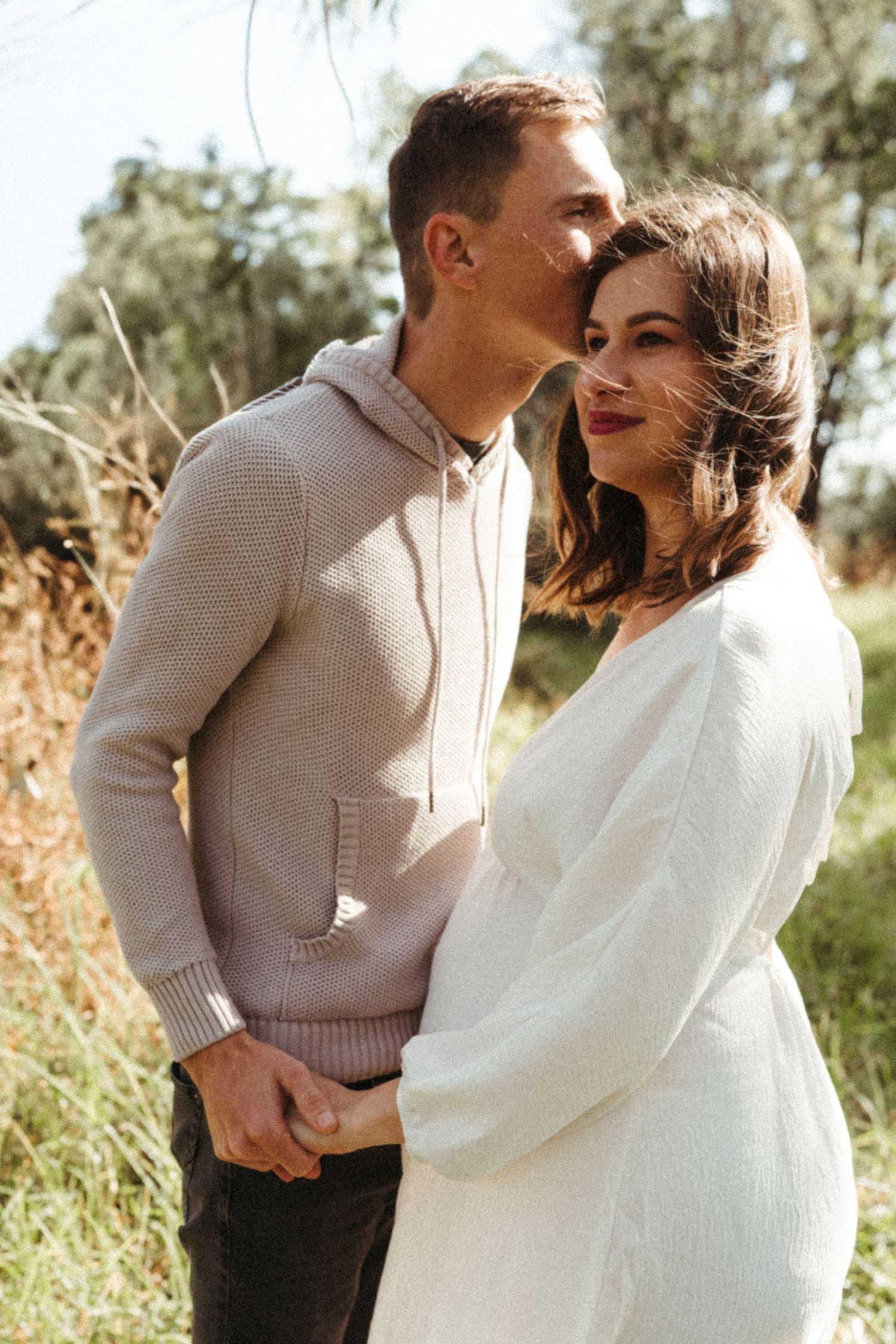 Sweet candid moments between a couple in warm sunlight and natural outdoor setting.