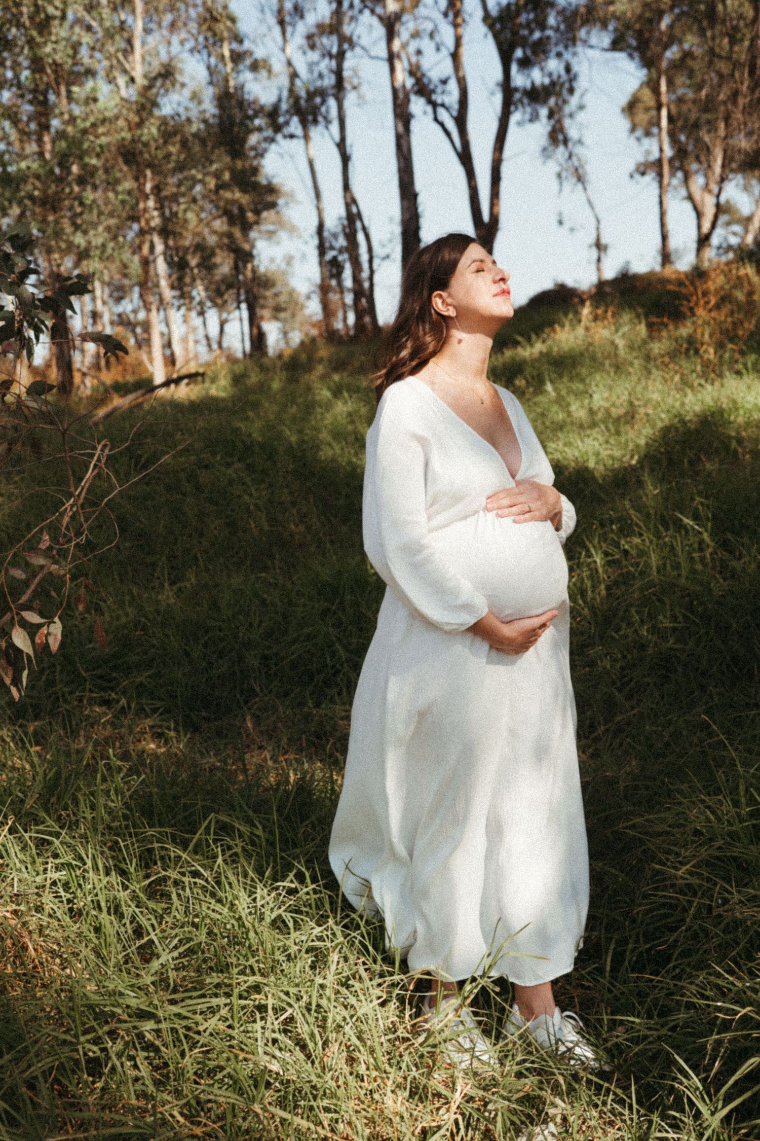 An intimate outdoor photoshoot with a couple embracing among tall grass and trees.