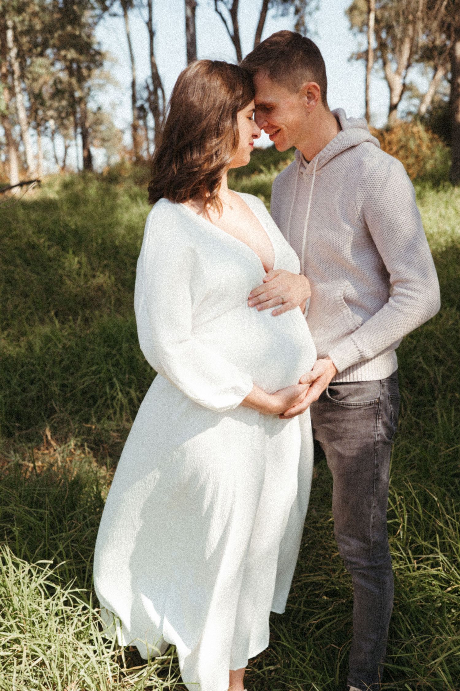 A couple shares affectionate moments during an outdoor photoshoot in nature.