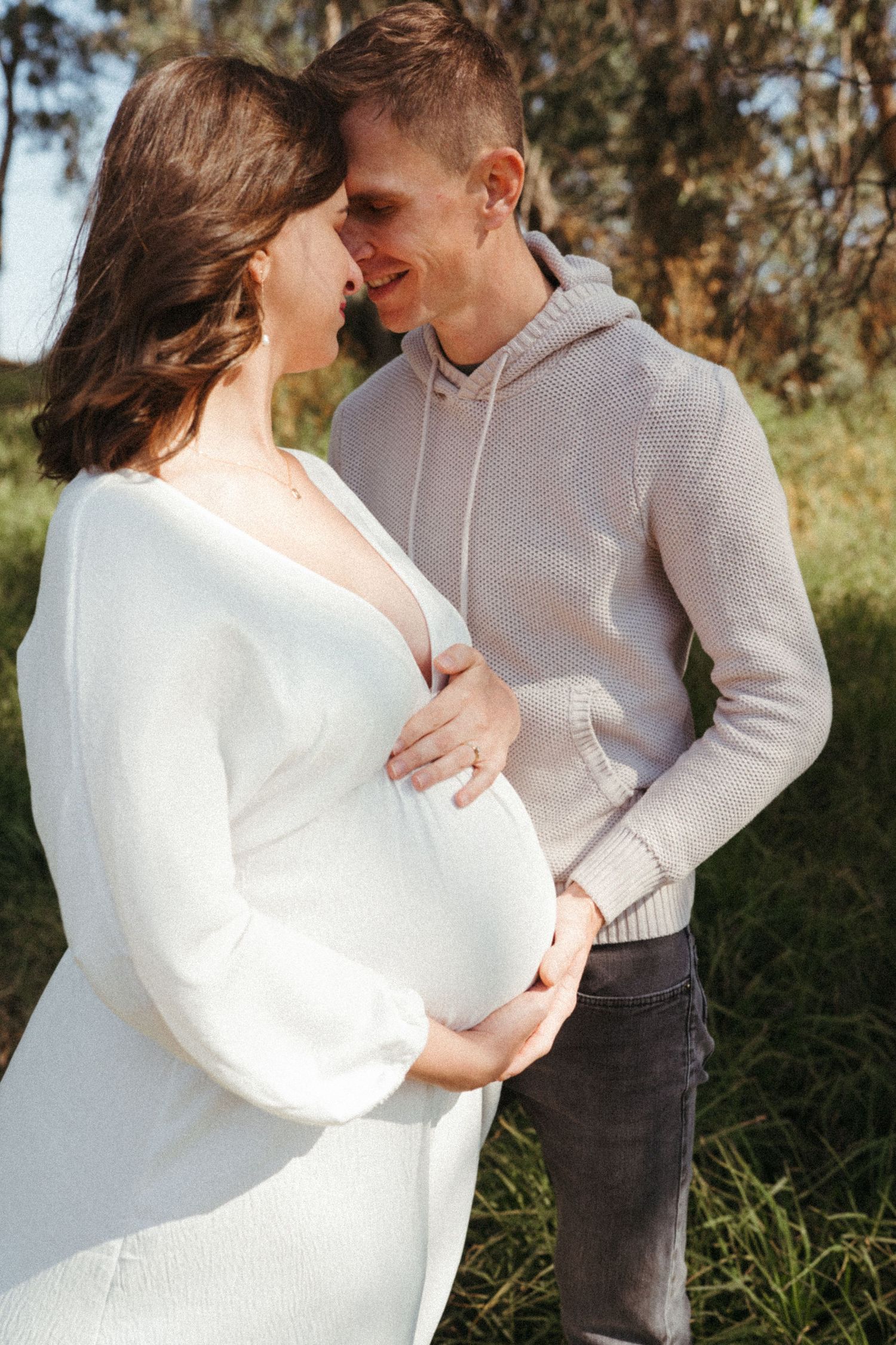 A couple embraces during a golden hour photoshoot in a natural outdoor setting.