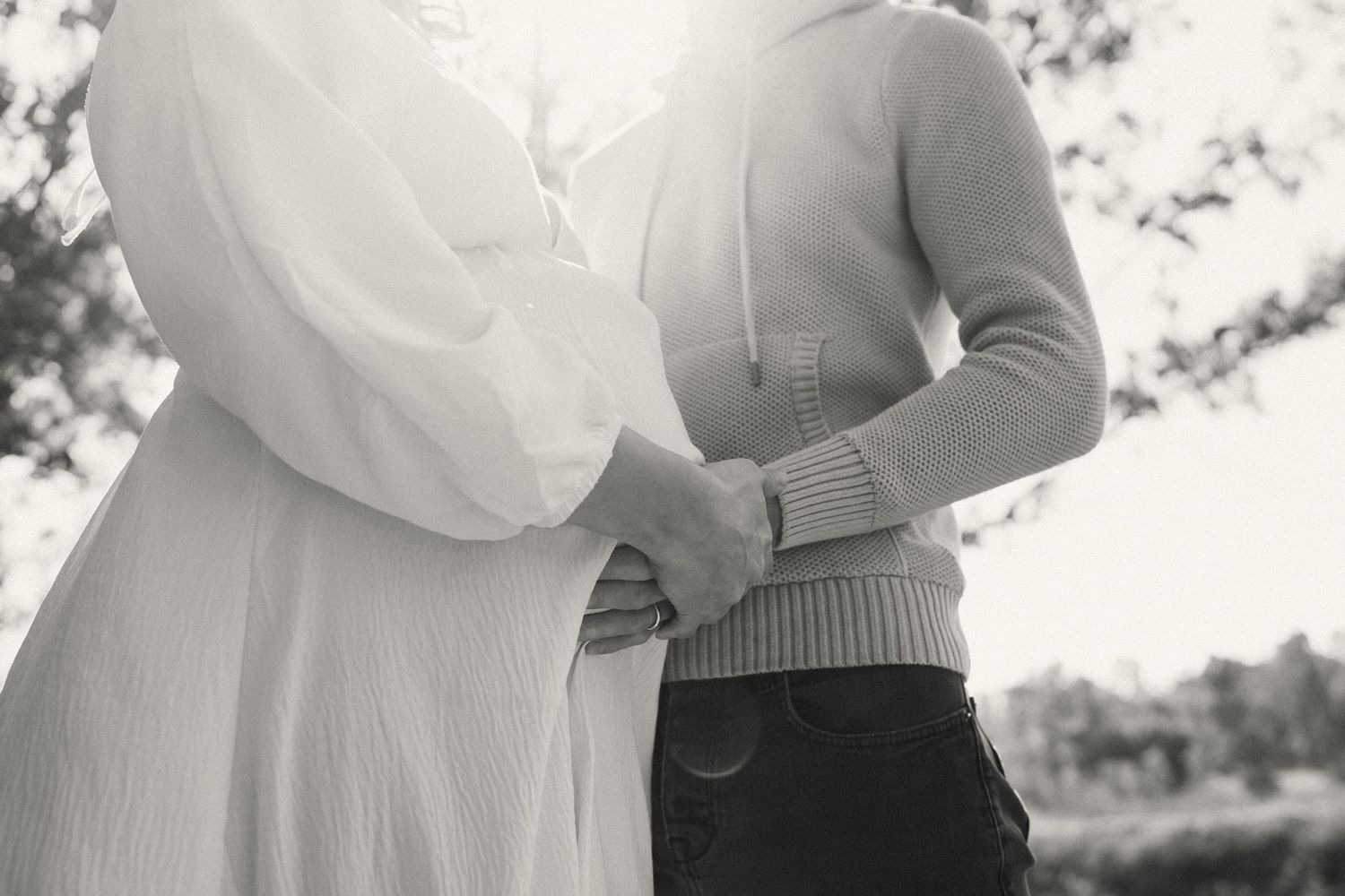 Two people share a romantic moment in soft sunlight wearing white and beige outfits.