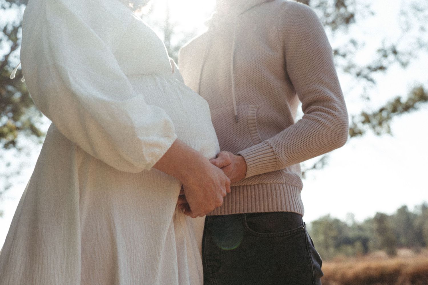 A romantic outdoor portrait showing gentle affection between two people in light colored clothing.