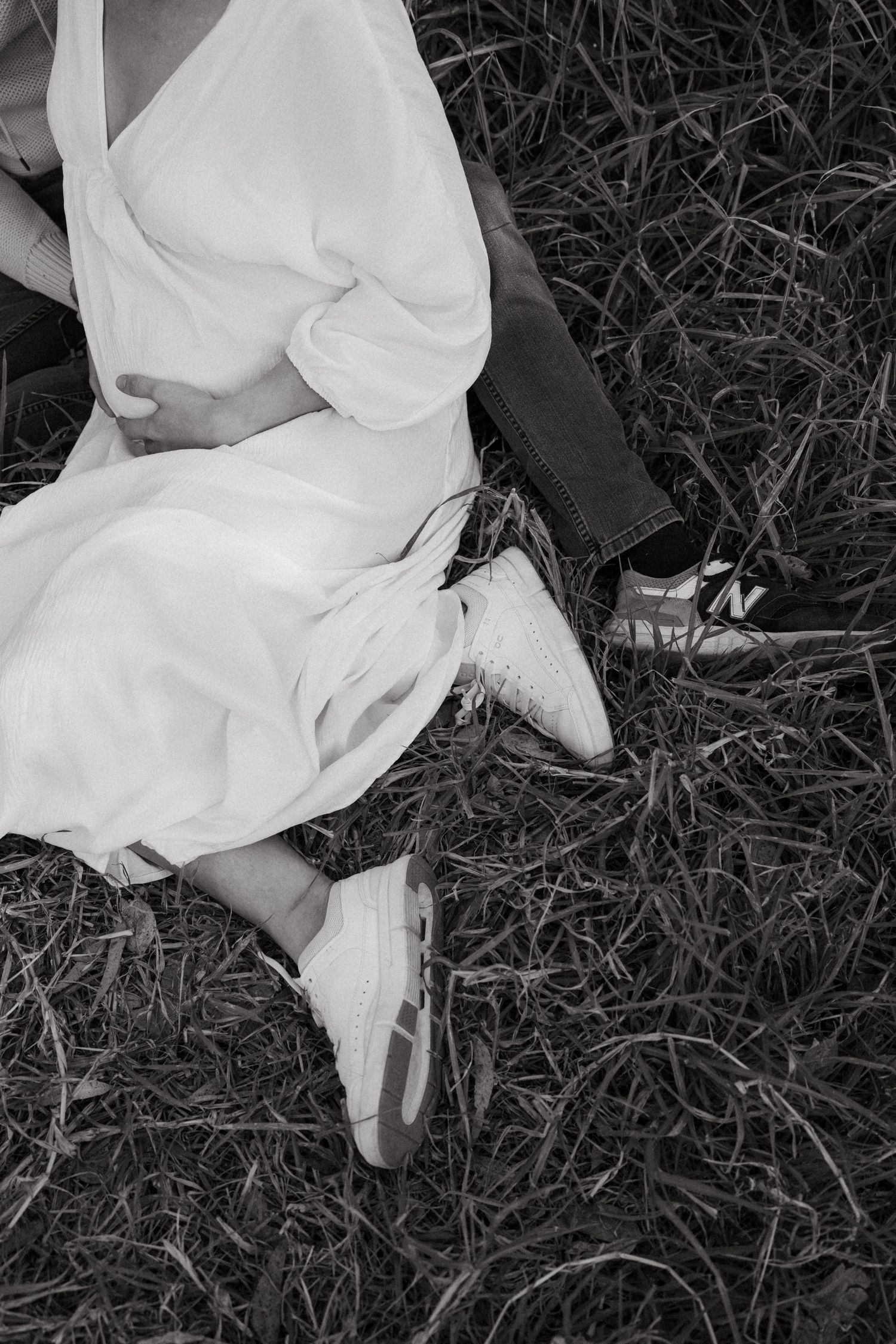 Black and white image showing the flowing fabric of a white dress against grass.
