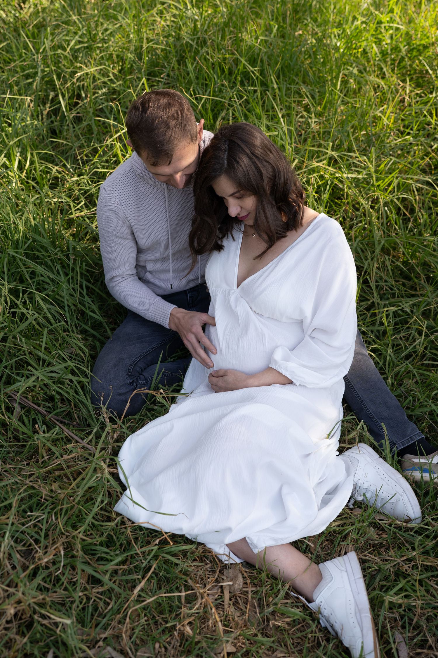 Loving couple embracing in a field of tall grass on a sunny afternoon.