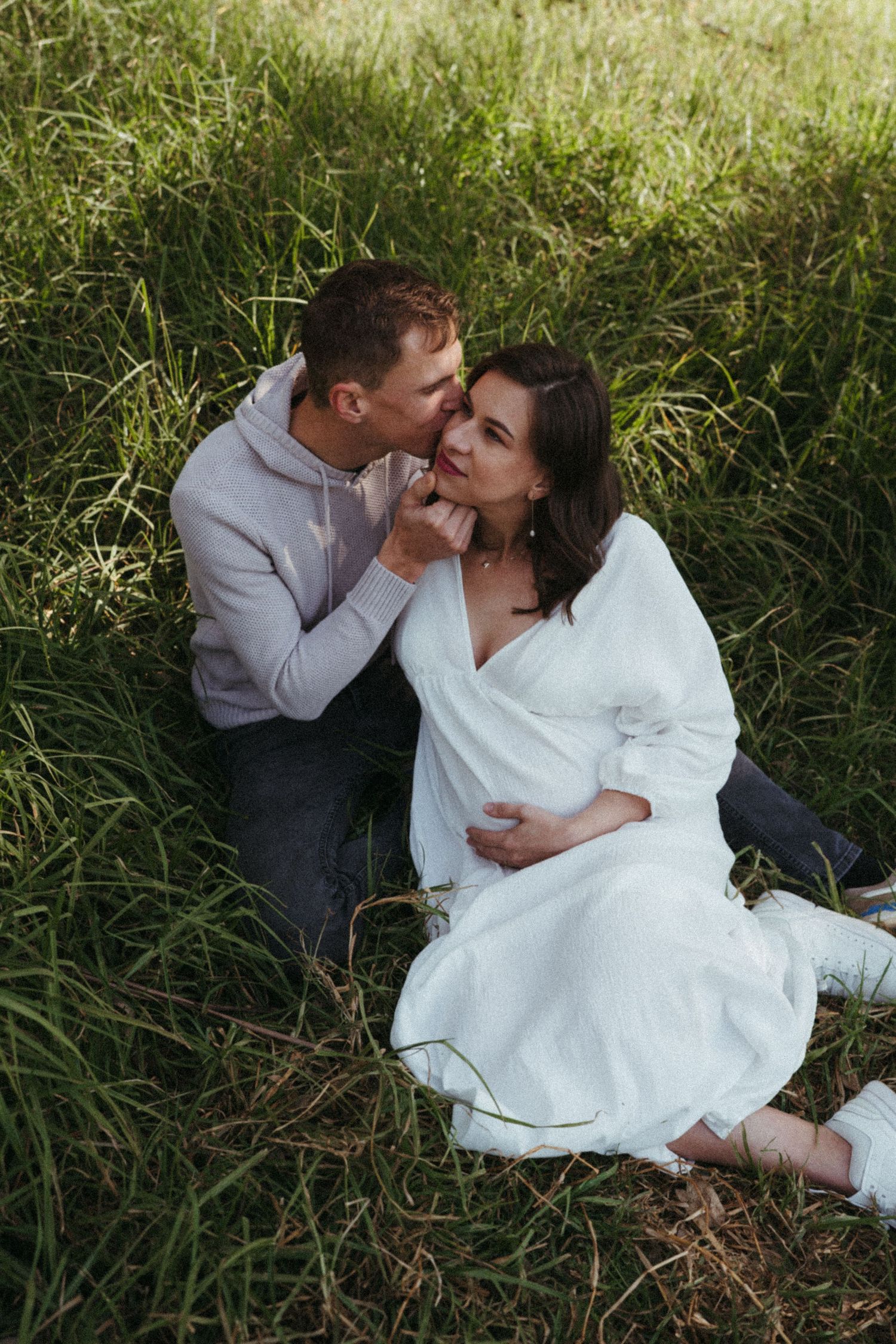 Intimate couple sharing tender moments together in a sunlit meadow.