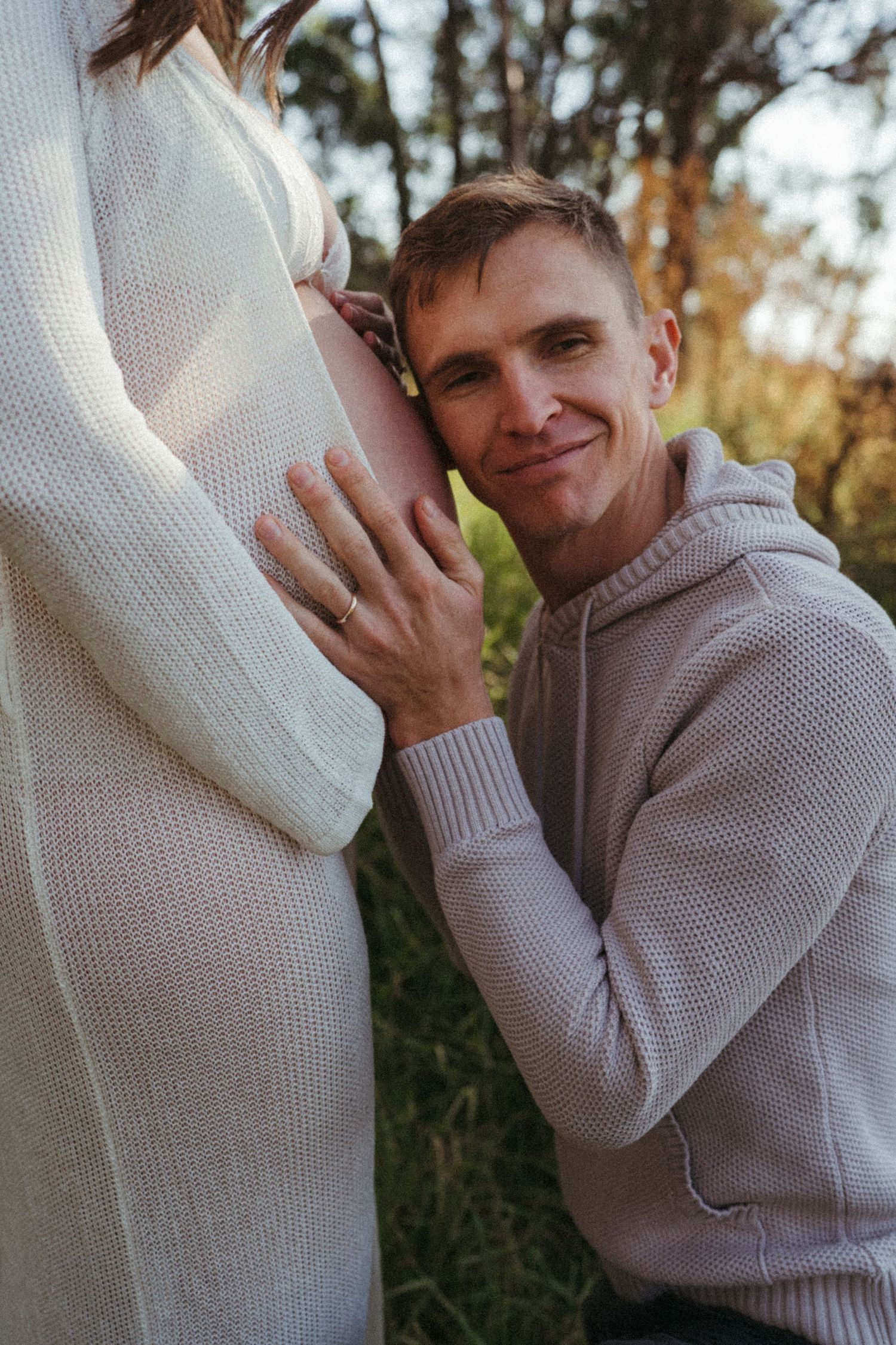 Sweet maternity photo showing affectionate moment in natural setting.