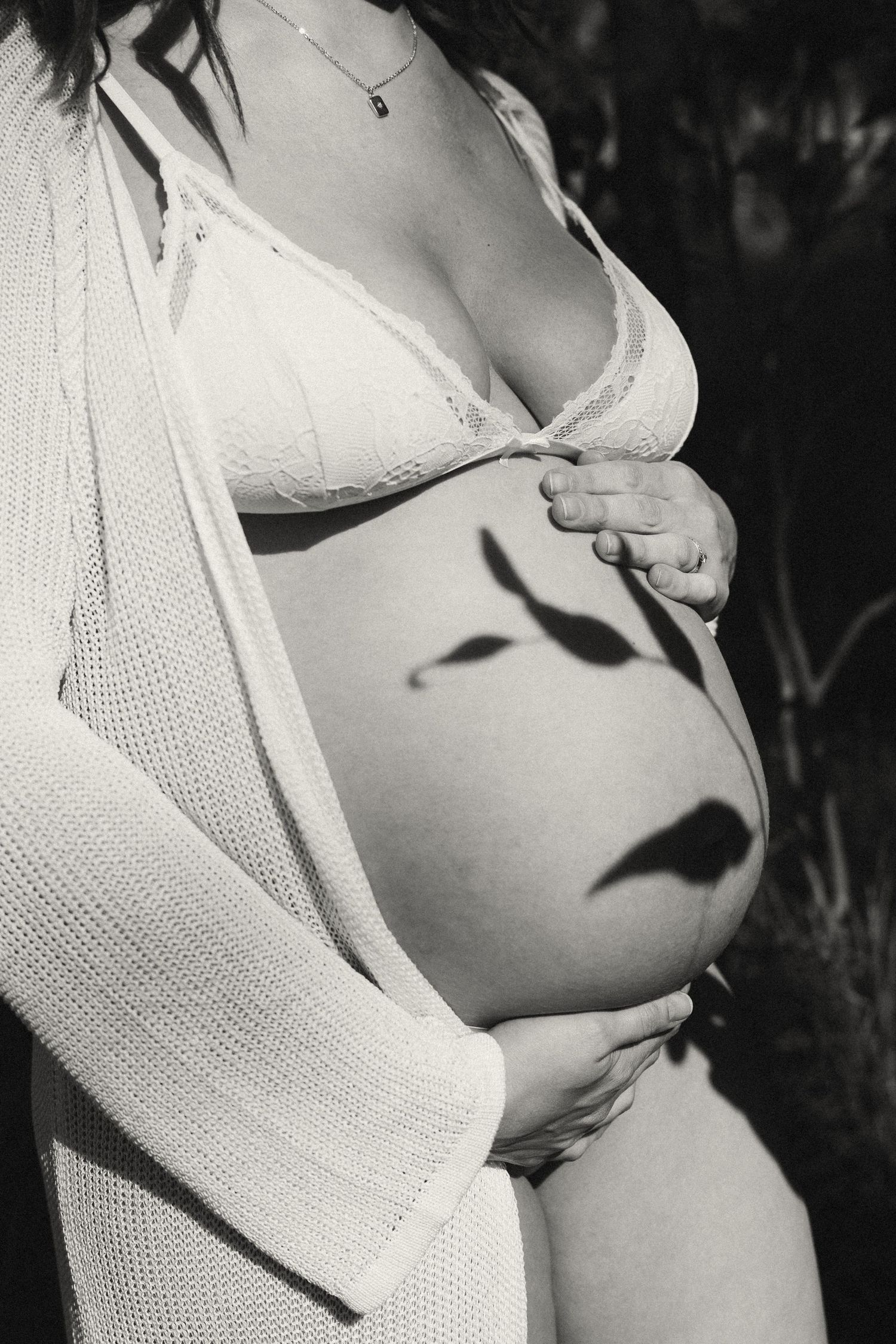 Artistic black and white maternity photo highlighting pregnant belly.