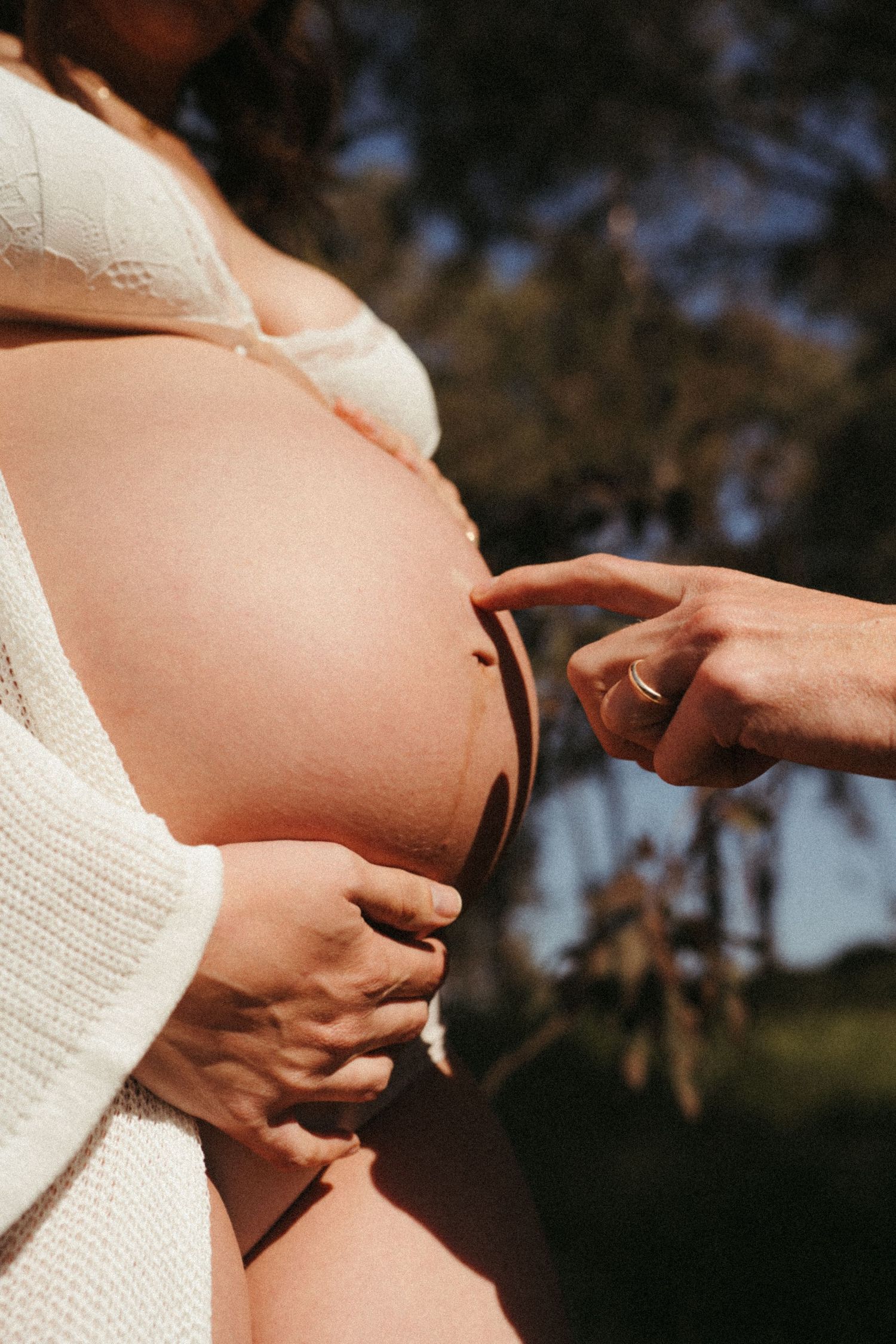 Intimate maternity portrait showing gentle hands on pregnant belly in natural light.